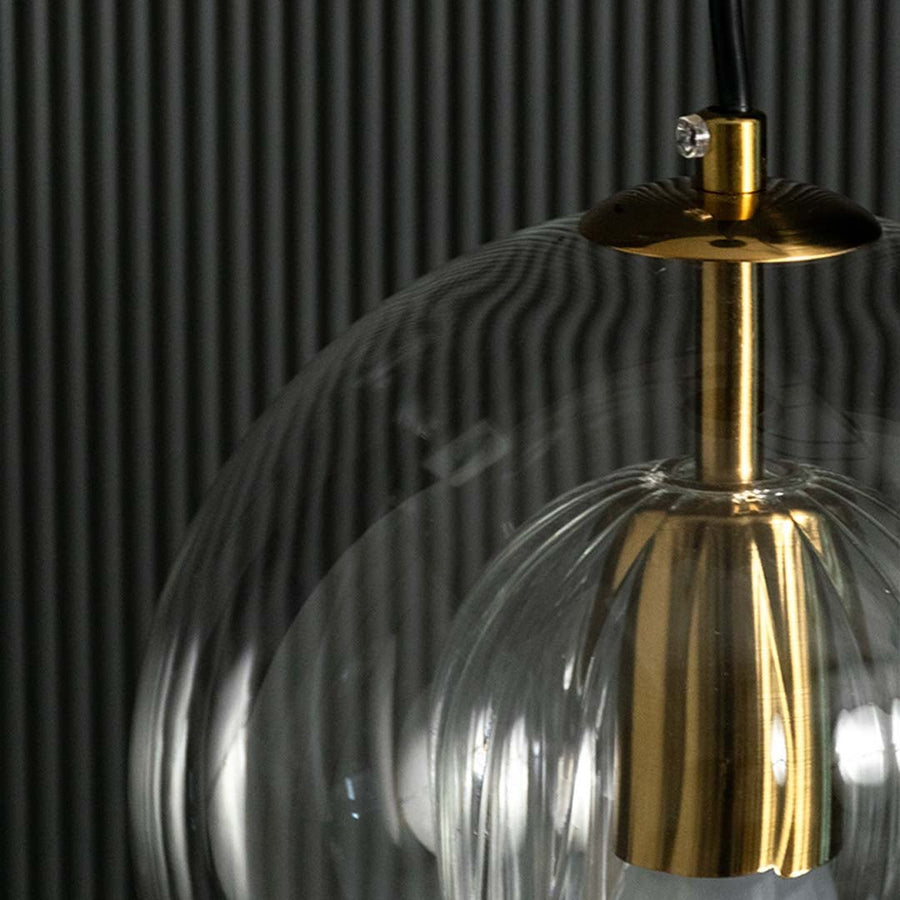Closeup of glass pendant light showing reflective smoked glass surface gold metal holder and elegant contemporary detailing.