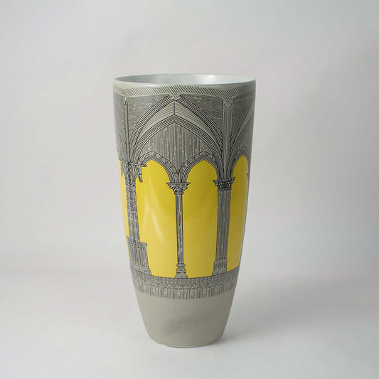 Tall ceramic vase with grey body and yellow abstract pattern placed on white surface against neutral background enhancing contemporary artistic home decor aesthetic.