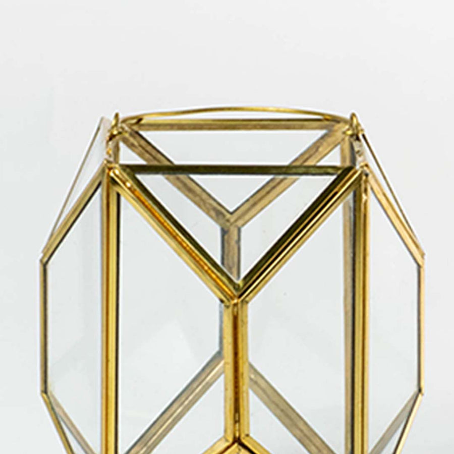 Closeup of gold geometric lantern highlighting refined metal edges and clear glass panels creating a premium modern decorative piece for interiors.