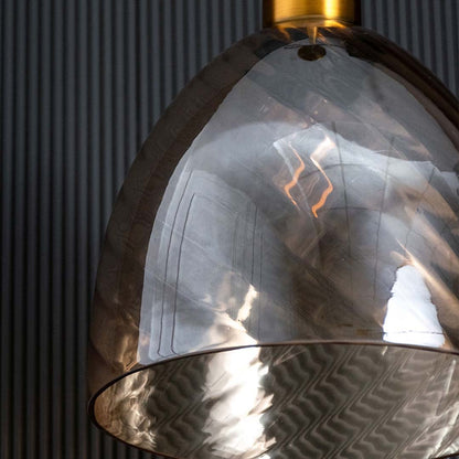 A closeup of the gold and smoked glass pendant light showing the swirled glass texture and metallic gold fitting ideal for premium interiors.