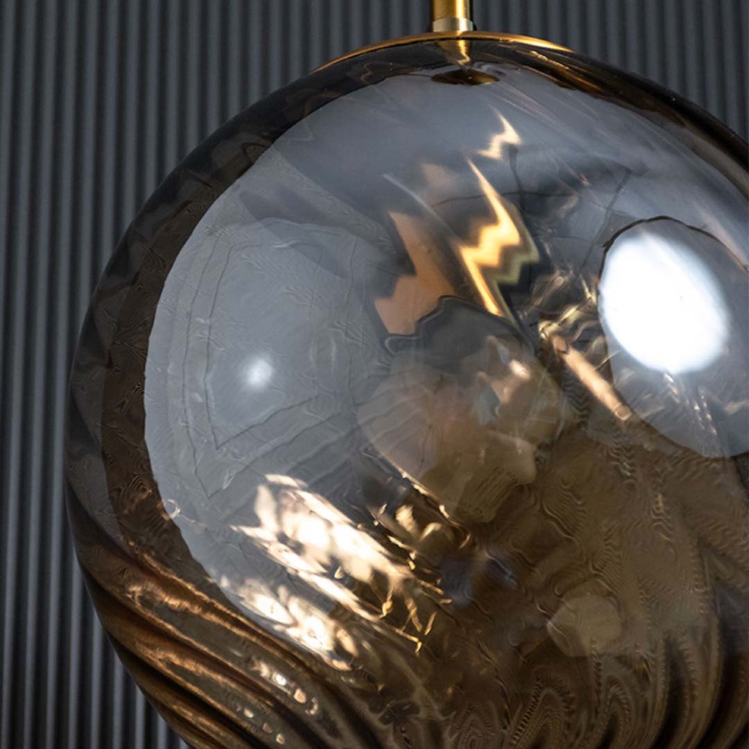 A detailed close view of the amber glass pendant light highlighting the curved glass texture and gold accents suited for luxury home styling.