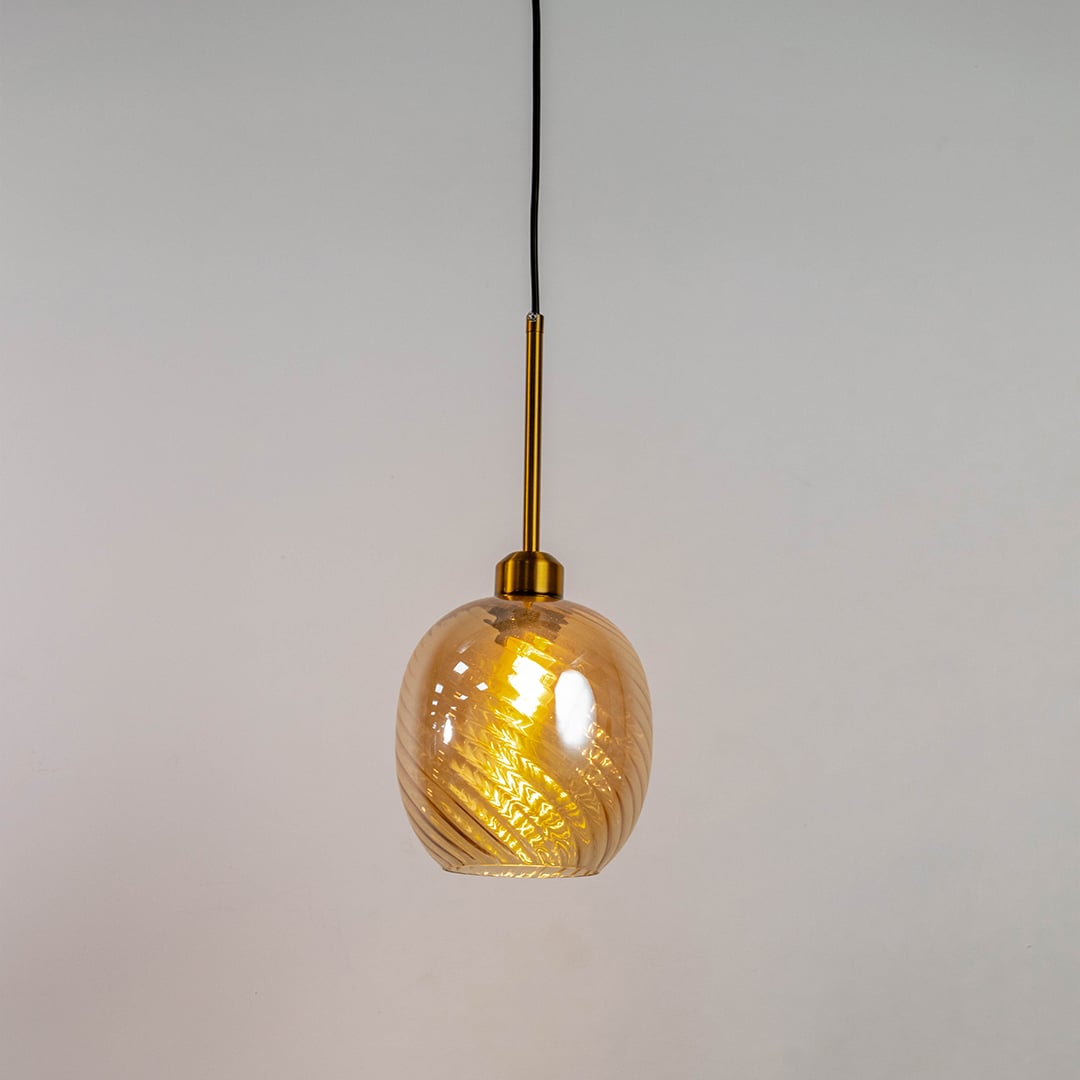 Illuminated gold pendant lamp with textured smoked glass shade isolated on white background highlighting warm spiral lighting pattern.