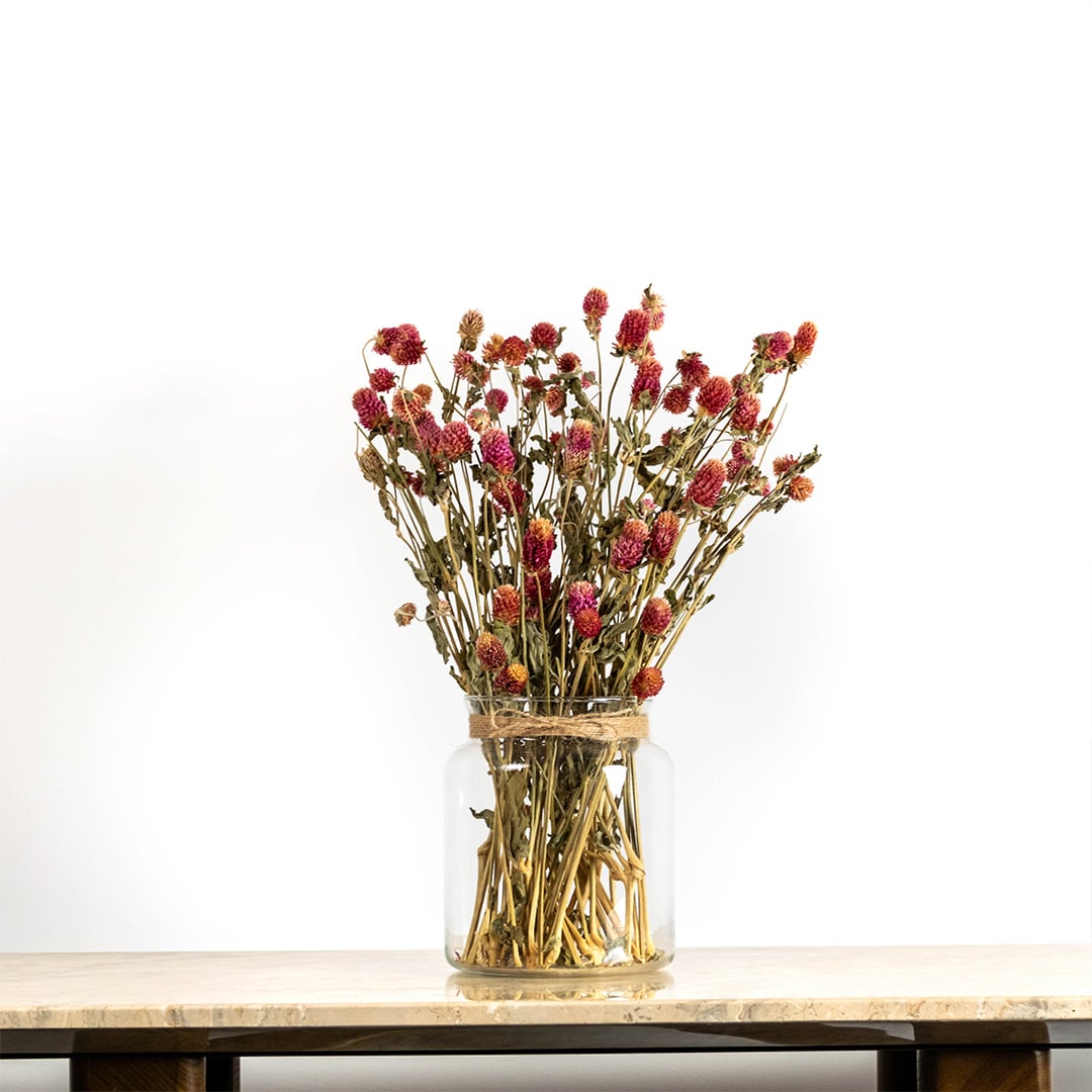 Purple dried flower arrangement in a clear glass vase displayed on a wooden table providing a vibrant natural décor accent suitable for elegant and modern room styling.