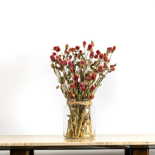 Purple dried flower arrangement in a clear glass vase displayed on a wooden table providing a vibrant natural décor accent suitable for elegant and modern room styling.