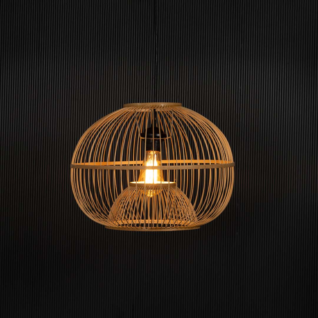 Rattan pendant light glowing on black background revealing its warm golden illumination and texture.