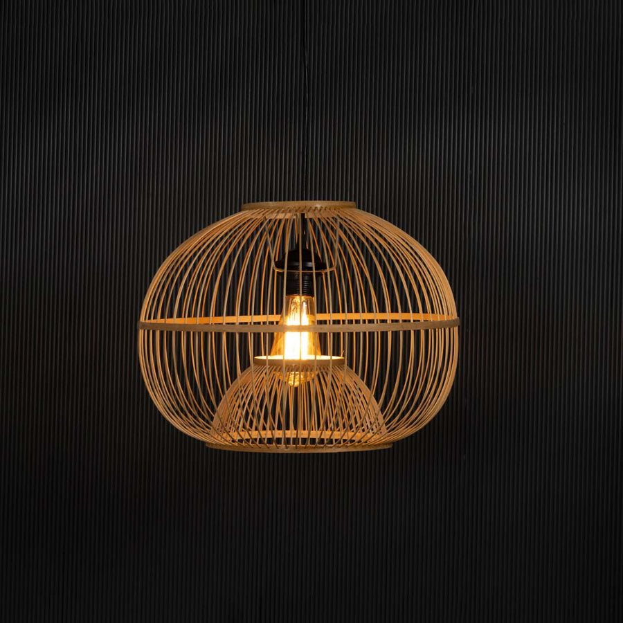 Rattan pendant light glowing on black background revealing its warm golden illumination and texture.