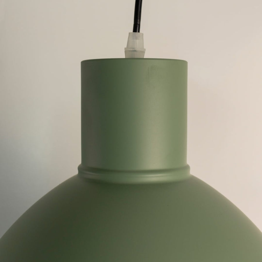 Detailed closeup view of the smooth matte green finish on the metal dome shade of the industrial pendant light fixture highlighting quality.