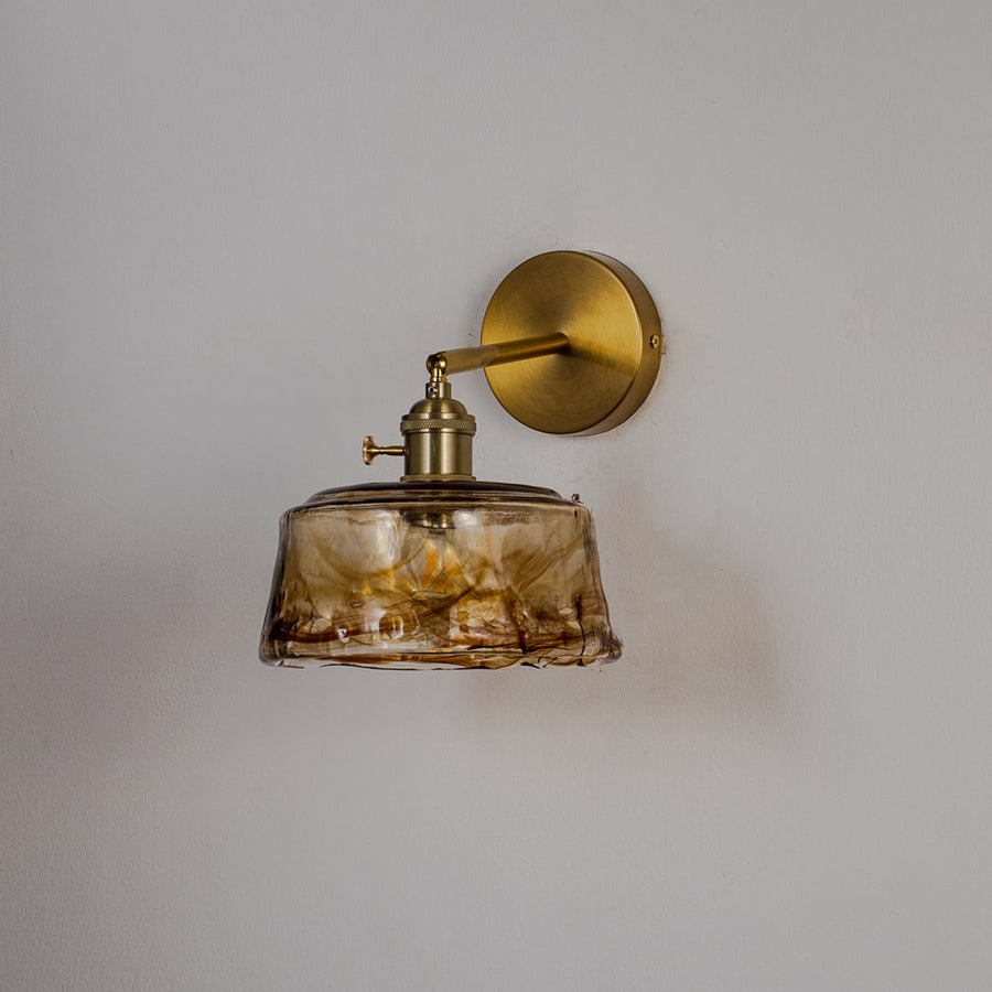 Vintage brass wall sconce with amber glass shade light off white background for bedroom living room and hallway decor.
