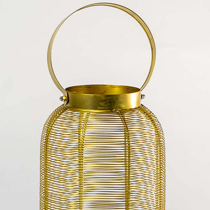 Closeup of gold metal mesh lantern with round handle for elegant modern decor styling use.