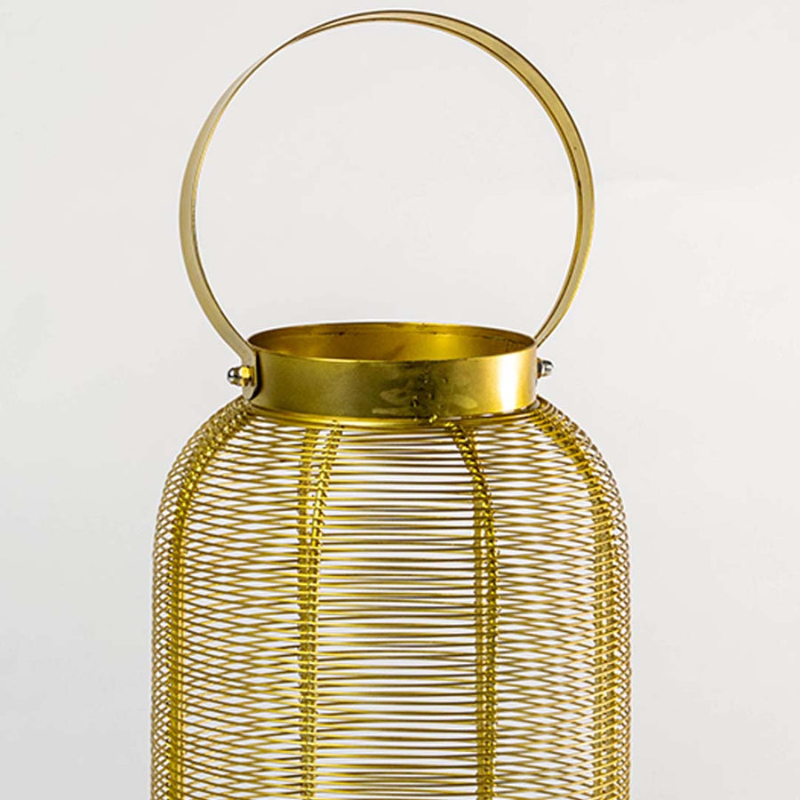 Closeup view of gold metal wire mesh texture and circular handle detail on decorative candle lantern with warm metallic finish.