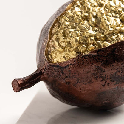 Closeup of golden pomegranate with detailed seed texture and glossy finish on marble base.
