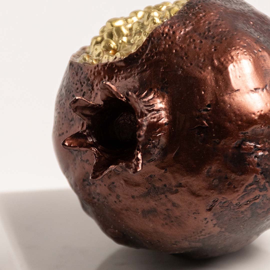 Closeup of golden pomegranate with detailed seed texture and glossy finish on marble base.
