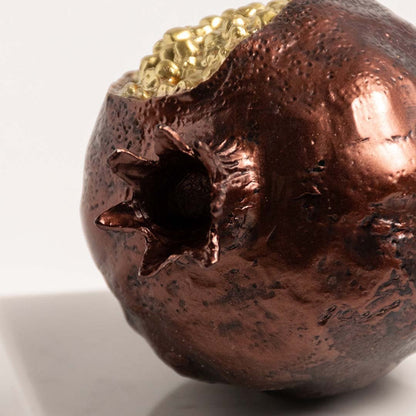 Closeup of golden pomegranate with detailed seed texture and glossy finish on marble base.