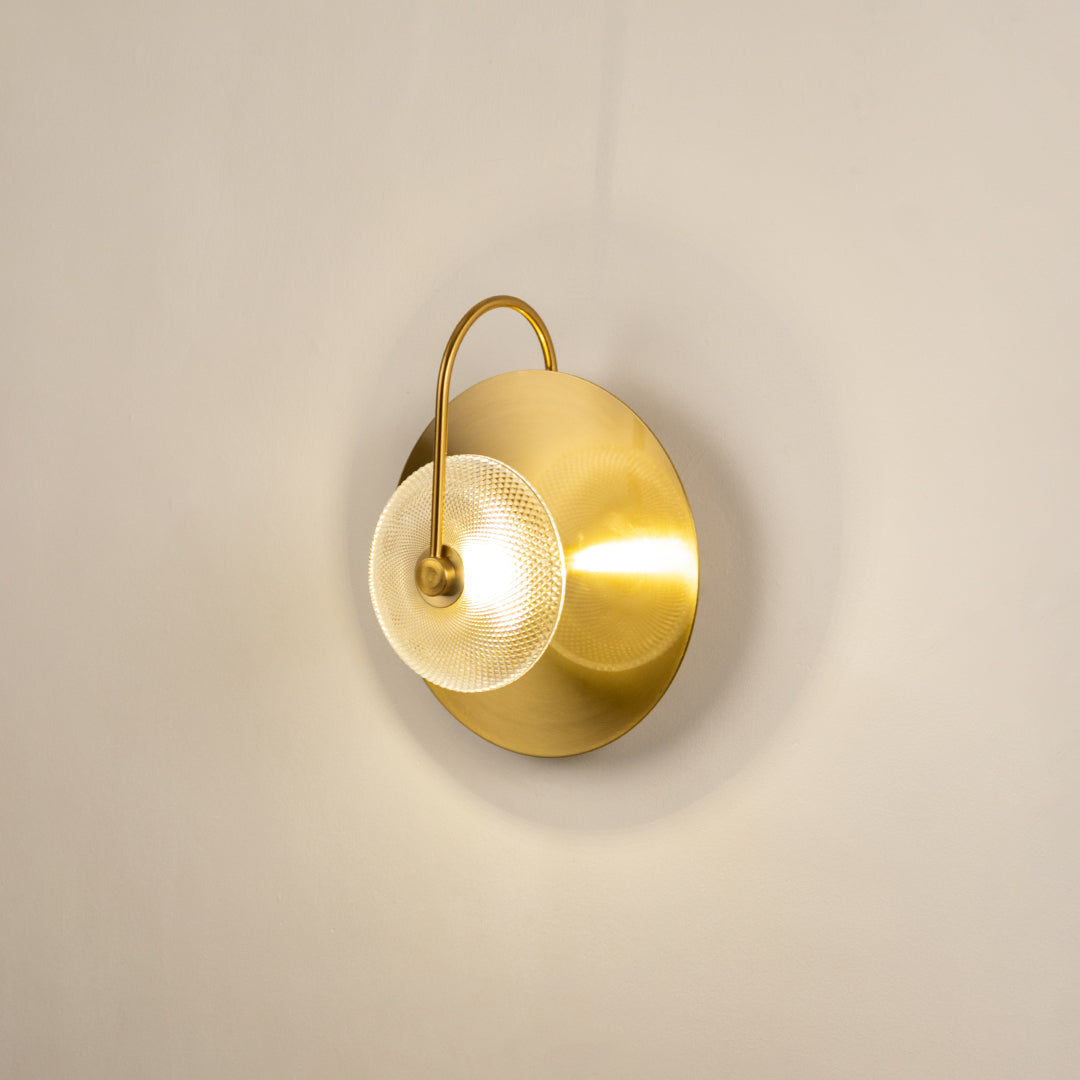 Elegant gold metal wall sconce with soft warm light fixed on neutral wall background ideal for minimal luxury interior lighting setup.
