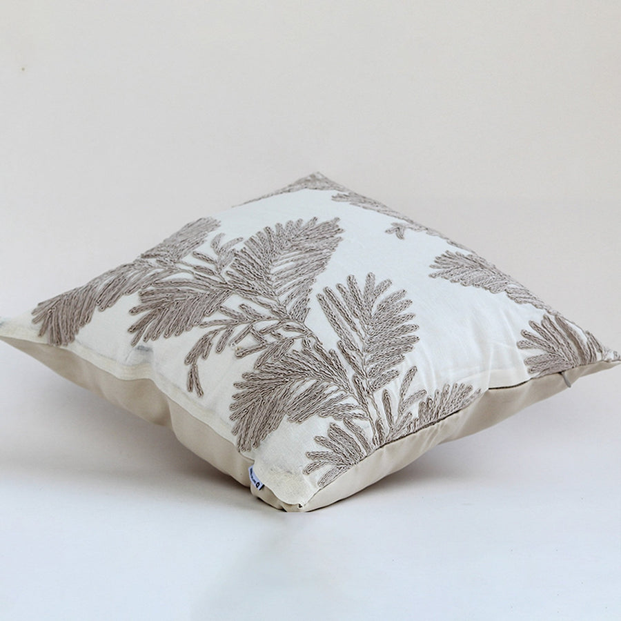Soft cotton cushion cover with beige botanical embroidery shown at an angle providing an elegant nature inspired décor accent with a breathable gentle and skin friendly material suited for modern décor.