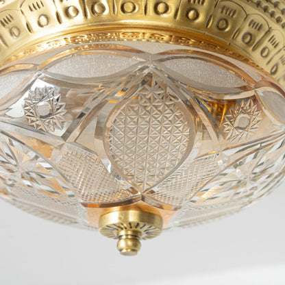 Detailed closeup of vintage ceiling light showing brass rim and intricate crystal cut glass pattern for elegant decor.