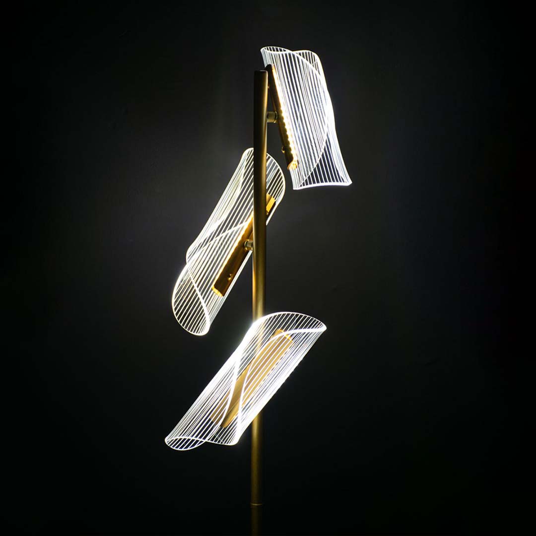 Closeup of glowing acrylic light panels on the gold floor lamp capturing their curved sculptural detailing and warm illuminated finish.