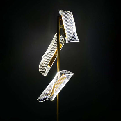 Closeup of glowing acrylic light panels on the gold floor lamp capturing their curved sculptural detailing and warm illuminated finish.