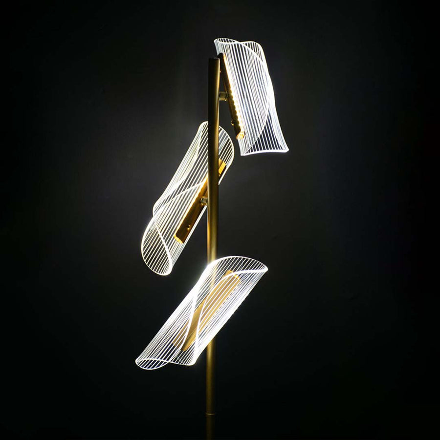 Closeup of glowing acrylic light panels on the gold floor lamp capturing their curved sculptural detailing and warm illuminated finish.