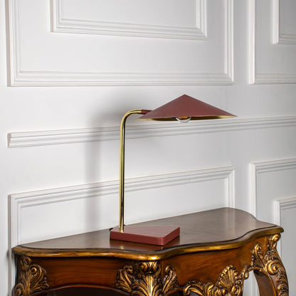 Modern brass desk lamp with geometric shade casting focused warm light for study desk and workspace illumination.