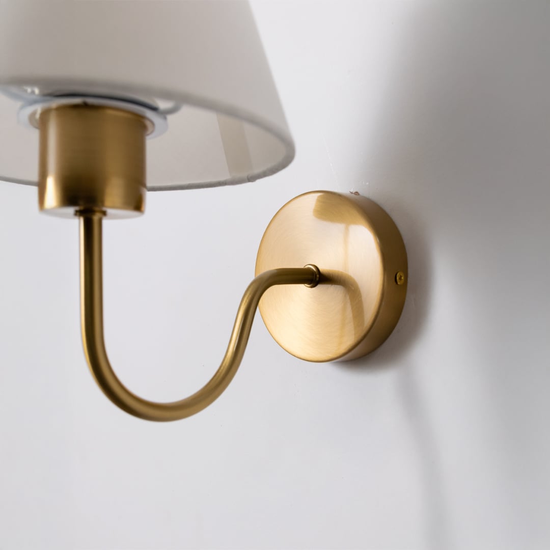Closeup view of the wall light highlighting the soft fabric shade and warm metal arm with clear detailing for a premium finish.