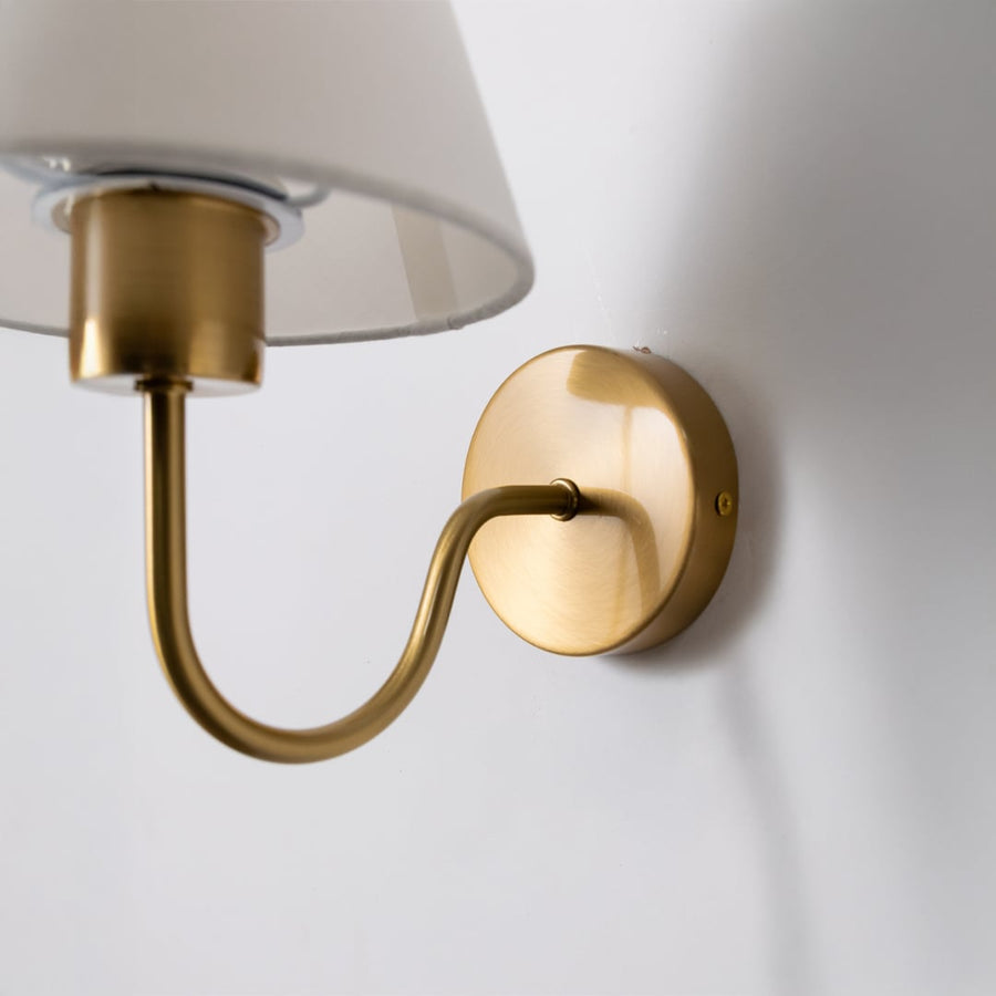 Closeup view of the wall light highlighting the soft fabric shade and warm metal arm with clear detailing for a premium finish.