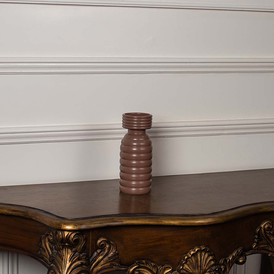 Terracotta brown ceramic column vase with a bold stacked horizontal ribbed pattern displayed on a classic console table.