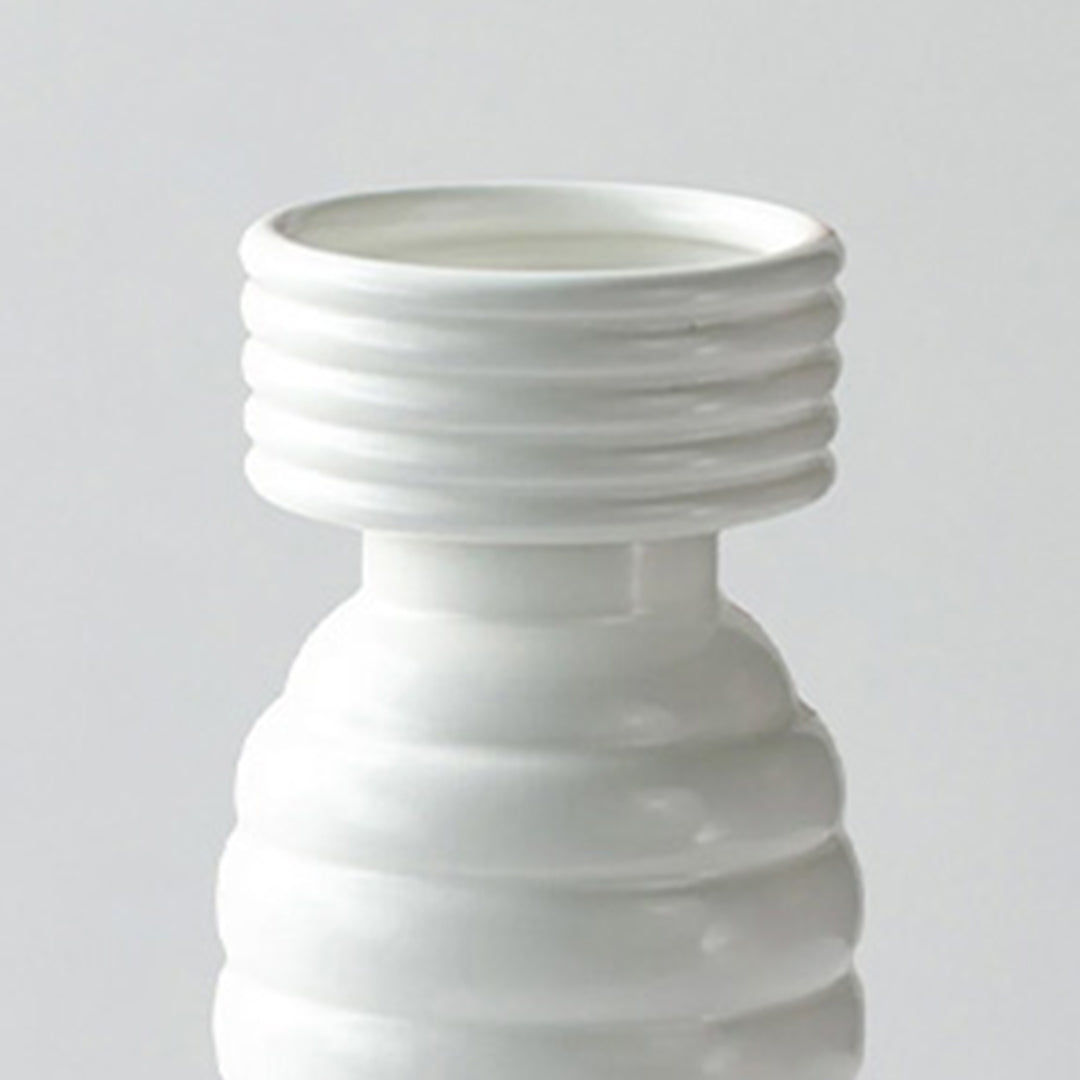 Sender closeup image of a glossy white ceramic totem vase featuring stacked ribbed tiers and a wide horizontally grooved neck.