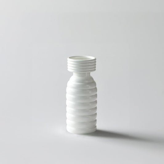 White background image of a modern ribbed white ceramic vase with a tall slender shape and smooth matte finish  styled simply.