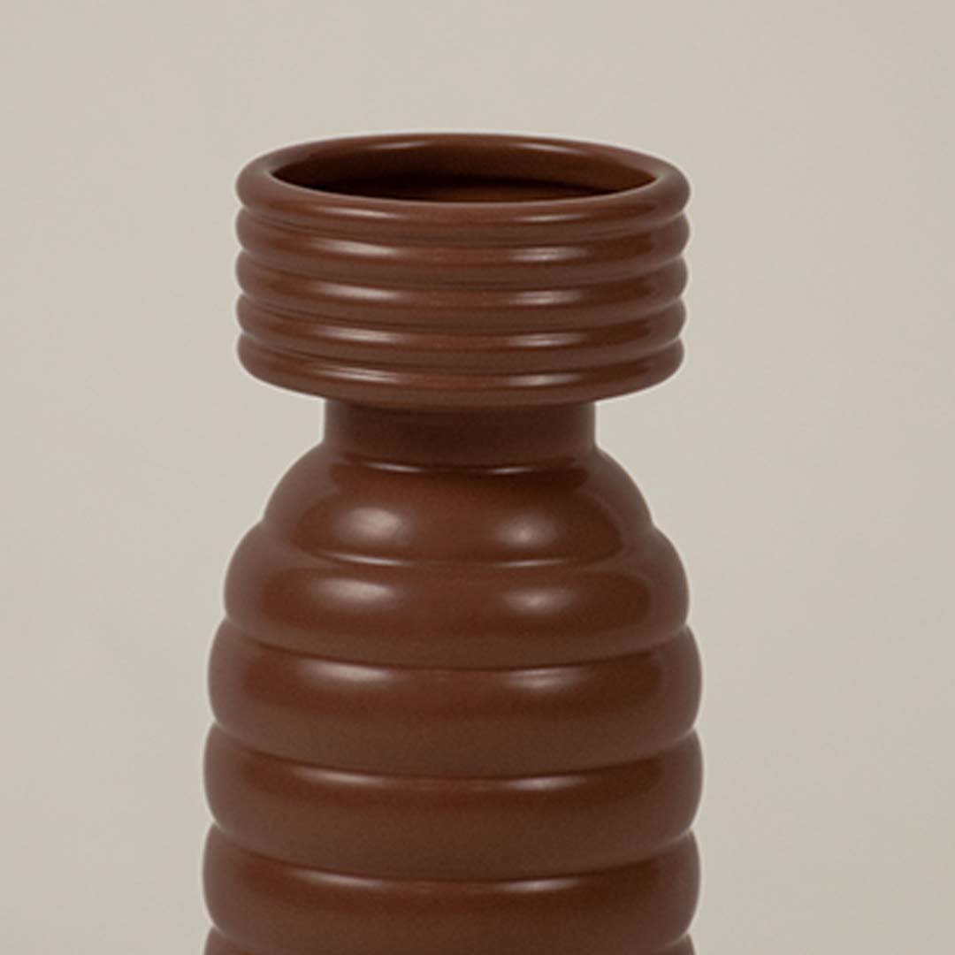 Closeup of brown ribbed ceramic vase showing its textured ridges and modern cylindrical handcrafted form.