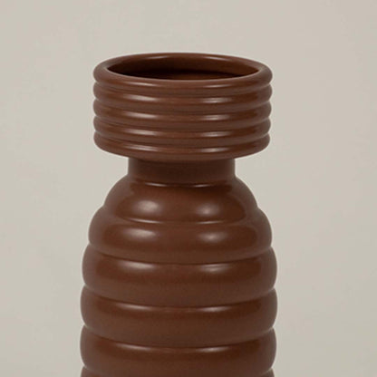 Closeup of brown ribbed ceramic vase showing its textured ridges and modern cylindrical handcrafted form.