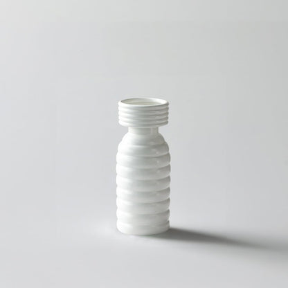 White background image of a modern ribbed white ceramic vase with a tall slender shape and smooth matte finish  styled simply.