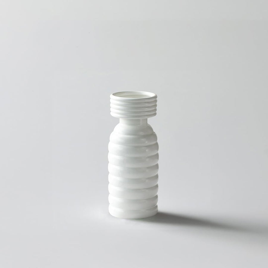 White background image of a modern ribbed white ceramic vase with a tall slender shape and smooth matte finish  styled simply.