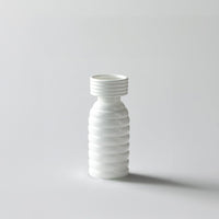 White background image of a modern ribbed white ceramic vase with a tall slender shape and smooth matte finish  styled simply.