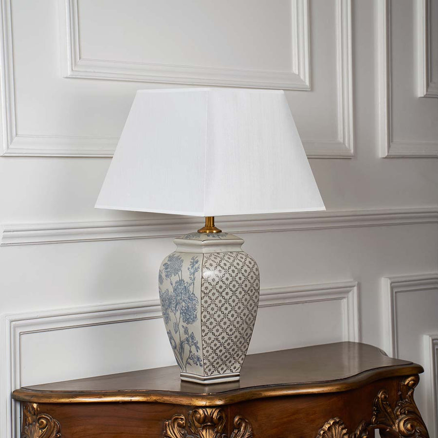 Decorative ceramic lamp with patterned base and white shade displayed on a plain white background with the light turned off.