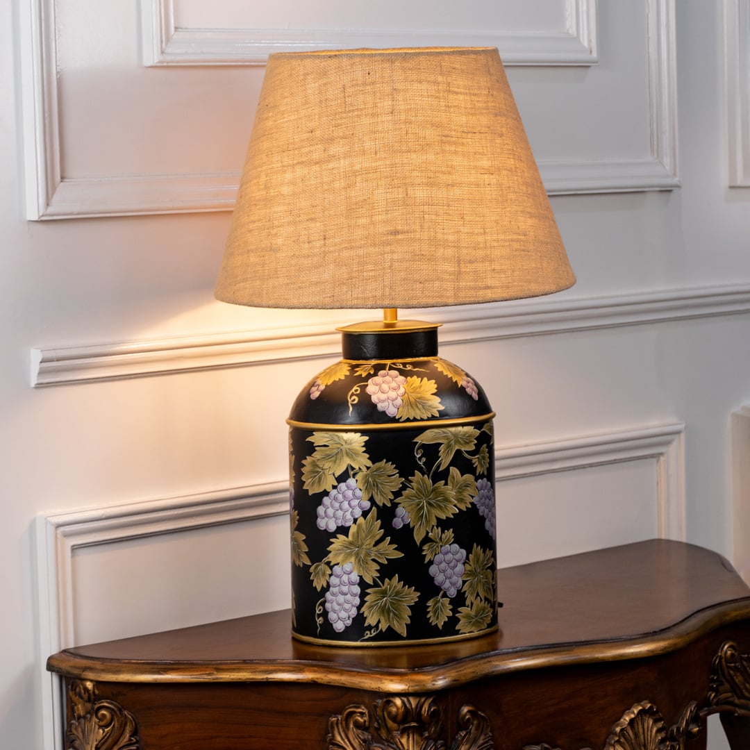 Grape Vine black table lamp illuminated on white background highlighting vine motif warm glow and bold interior decor styling.