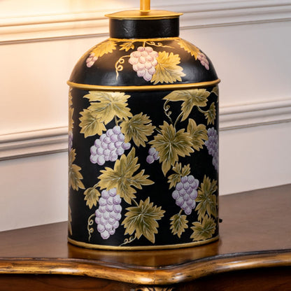 Table lamp closeup featuring dark ceramic base with floral artwork and elegant contrasting fabric shade.