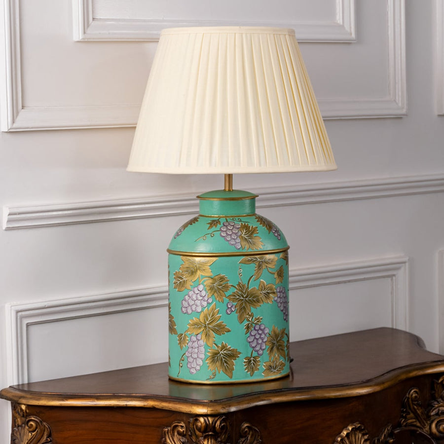 Palais mint green ceramic lamp with cream pleated shade turned off on white background displaying golden grapevine artwork.