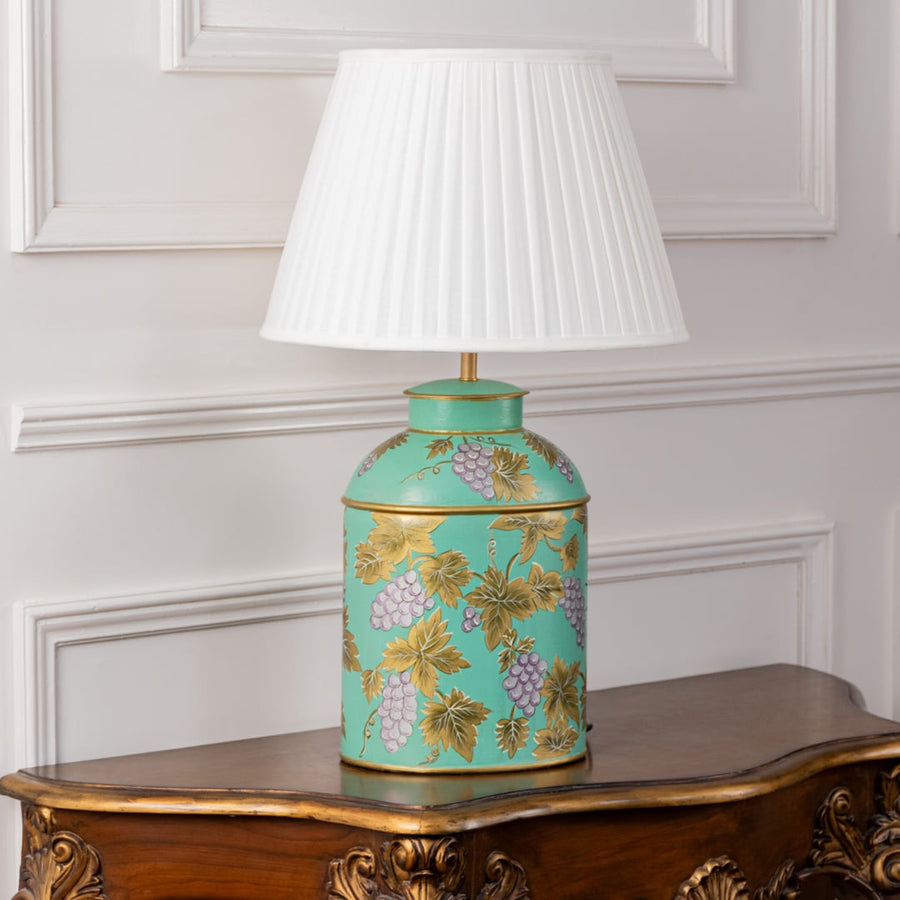 Palais mint green ceramic table lamp with golden grape design and white pleated shade turned off on white background decor setup.