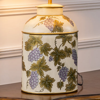 Table lamp closeup featuring a cream ceramic base decorated with green botanical leaf designs and subtle texture.
