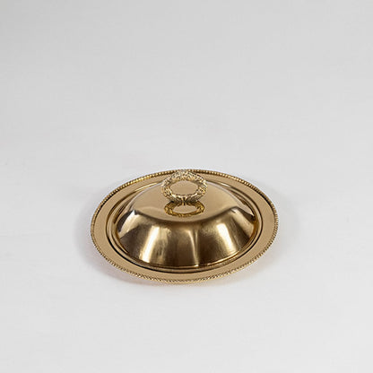 Gold dome lid with round handle displayed on white background highlighting reflective metal and clean design.