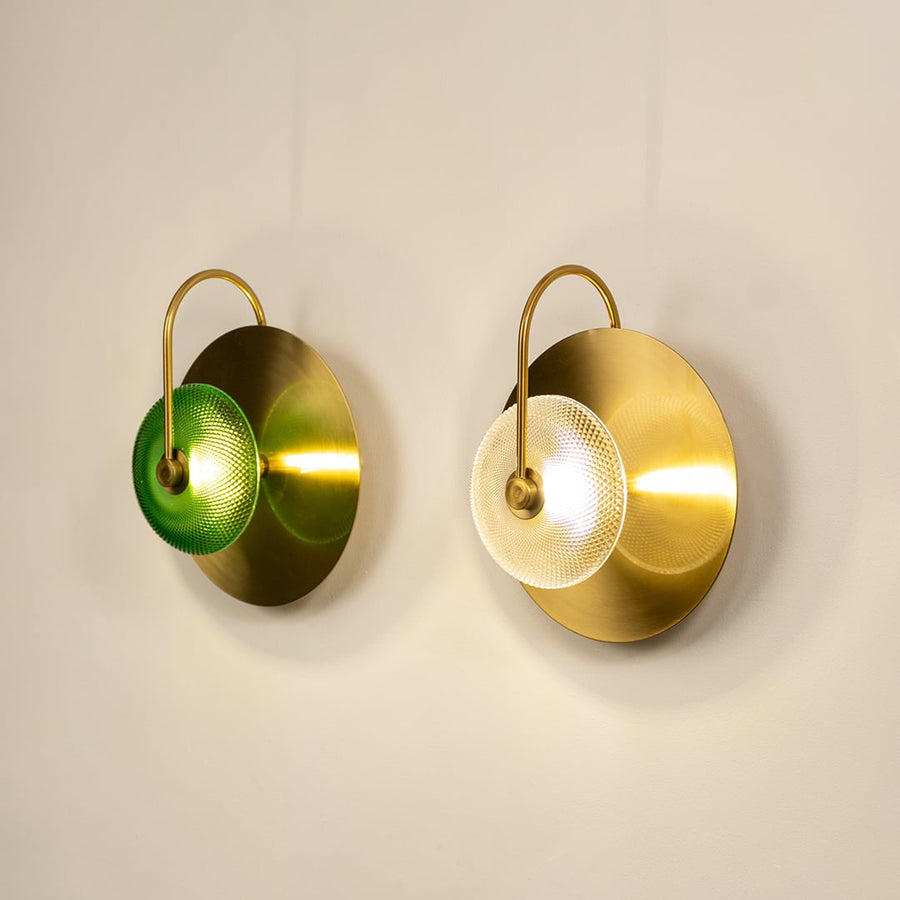 Elegant set of brass and green glass wall lights creating warm ambient glow in stylish living room setting.
