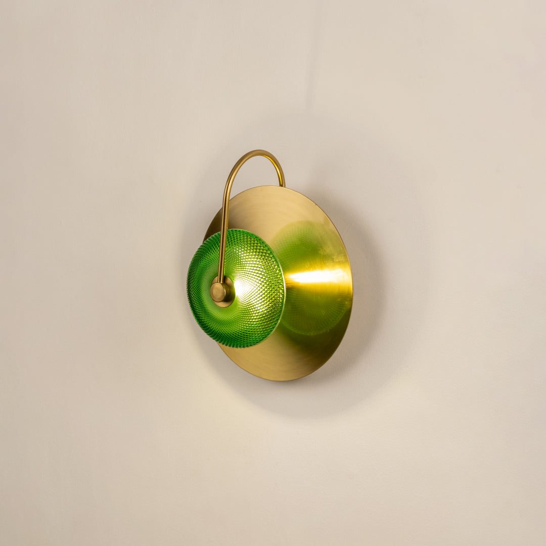 Decorative green glass wall light with gold metal base mounted on soft neutral wall background perfect for contemporary home decor lighting.

