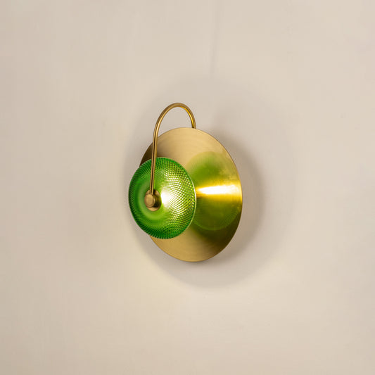 Decorative green glass wall light with gold metal base mounted on soft neutral wall background perfect for contemporary home decor lighting.

