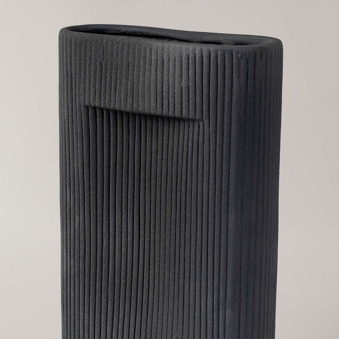 Closeup of tall black ceramic vase with vertical ribbed texture highlighting modern handcrafted detail for stylish home decor.