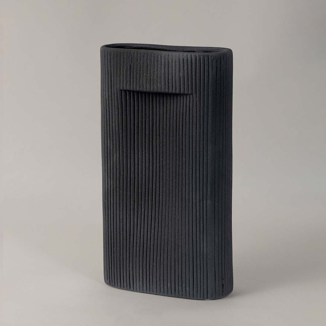 Contemporary black ceramic vase with ribbed detailing styled for modern minimalist home interiors on plain white background.