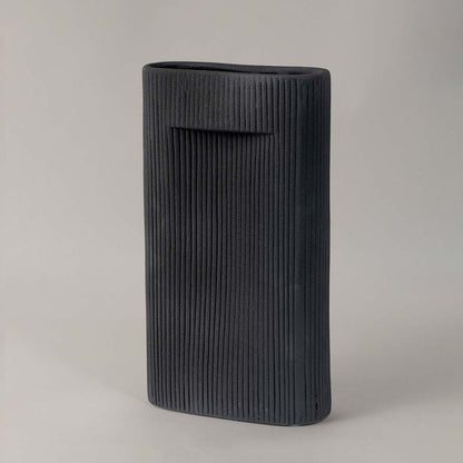Contemporary black ceramic vase with ribbed detailing styled for modern minimalist home interiors on plain white background.