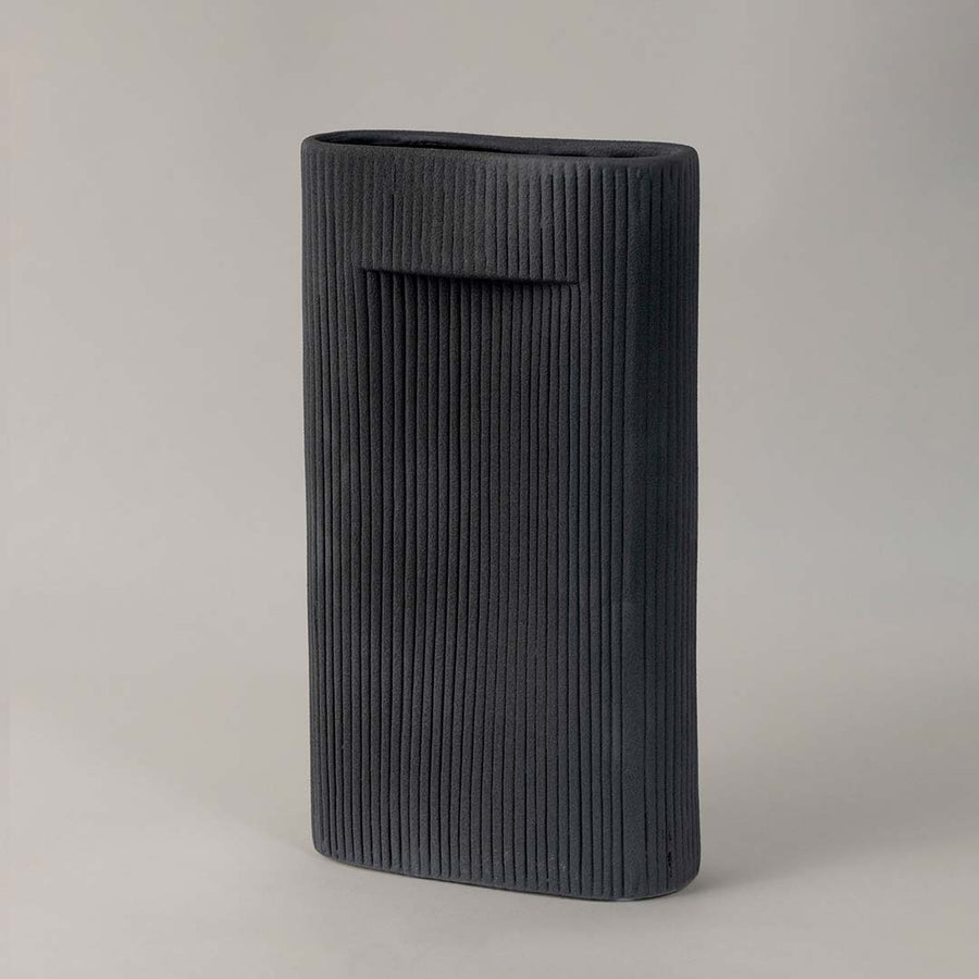 Contemporary black ceramic vase with ribbed detailing styled for modern minimalist home interiors on plain white background.