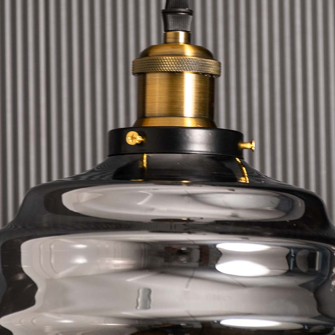Detailed closeup of the rippled smoked glass pendant light showing the curved glass texture and brass fitting with subtle reflections enhancing the elegant modern design.