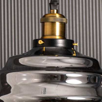 Detailed closeup of the rippled smoked glass pendant light showing the curved glass texture and brass fitting with subtle reflections enhancing the elegant modern design.